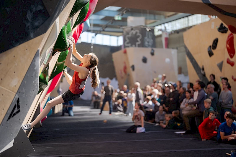 Junge Athletin bei der Schweizer Bouldern-Meisterschaft in Baden 2024, aufgenommen von Fotograf Manuel Lopez. Die Veranstaltung, organisiert vom Schweizer Alpen-Club (SAC), zeigt spannende Wettkämpfe in den Altersklassen U12, U14 und U16.